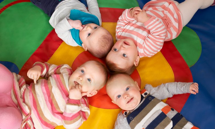 Overhead picture of two sets of twins lying on their backs