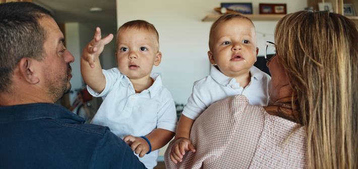 grandparents holding their twin baby boys in a living room