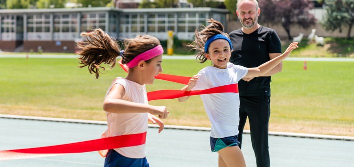 Twin girls cross the finishing line in a running race together