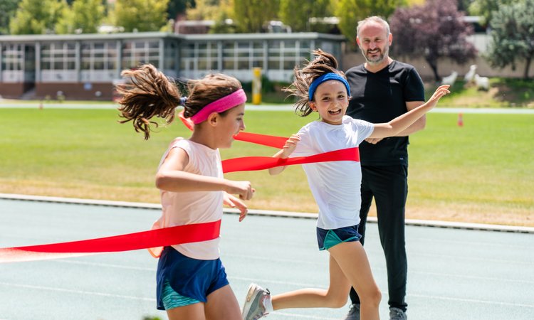 Twin girls cross the finishing line in a running race together