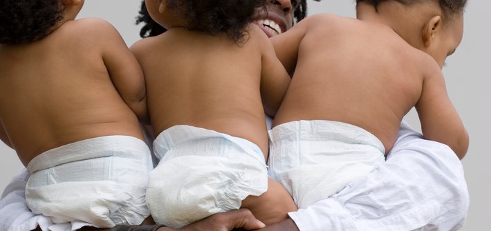 A closeup picture of a person's arms around triplet babies