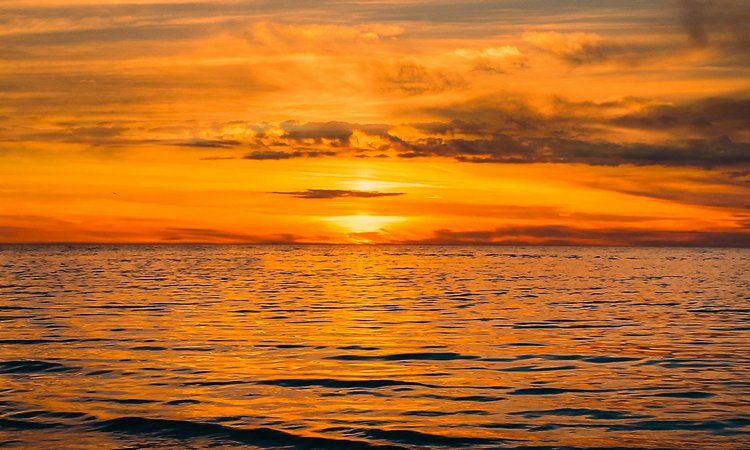 A sunset in the distance over a calm ocean