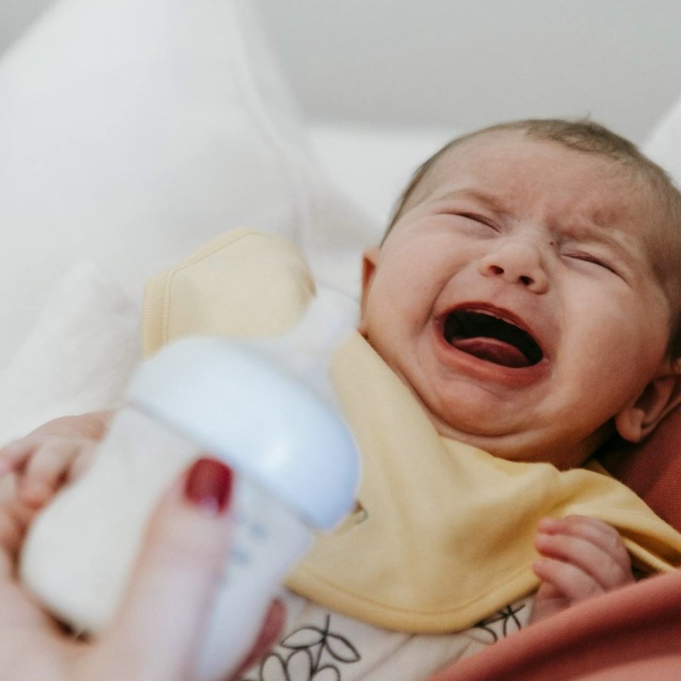 baby crying with a bottle of milk in the foreground