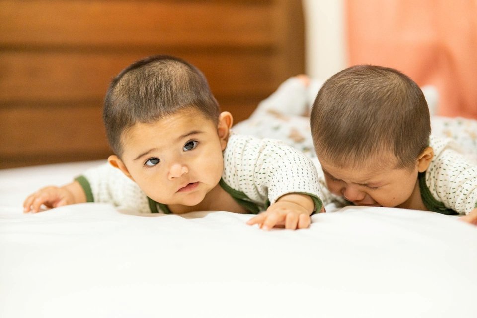 twin babies on a bed for tummy time