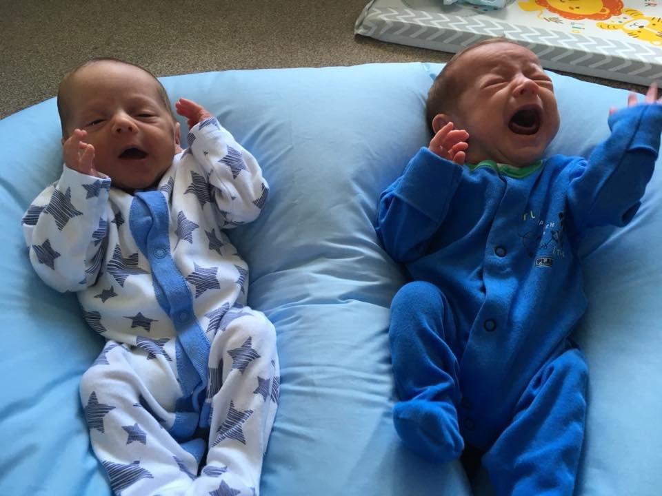 crying twin babies lying on a feeding pillow