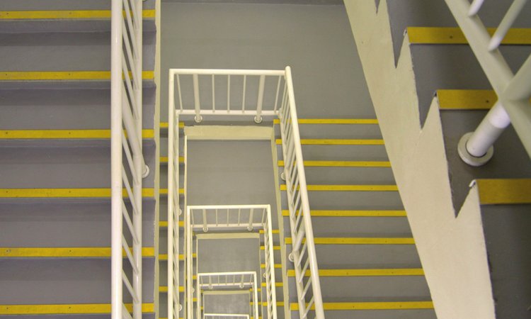 A looping stairwell covering multiple floors is seen looking down from a high floor
