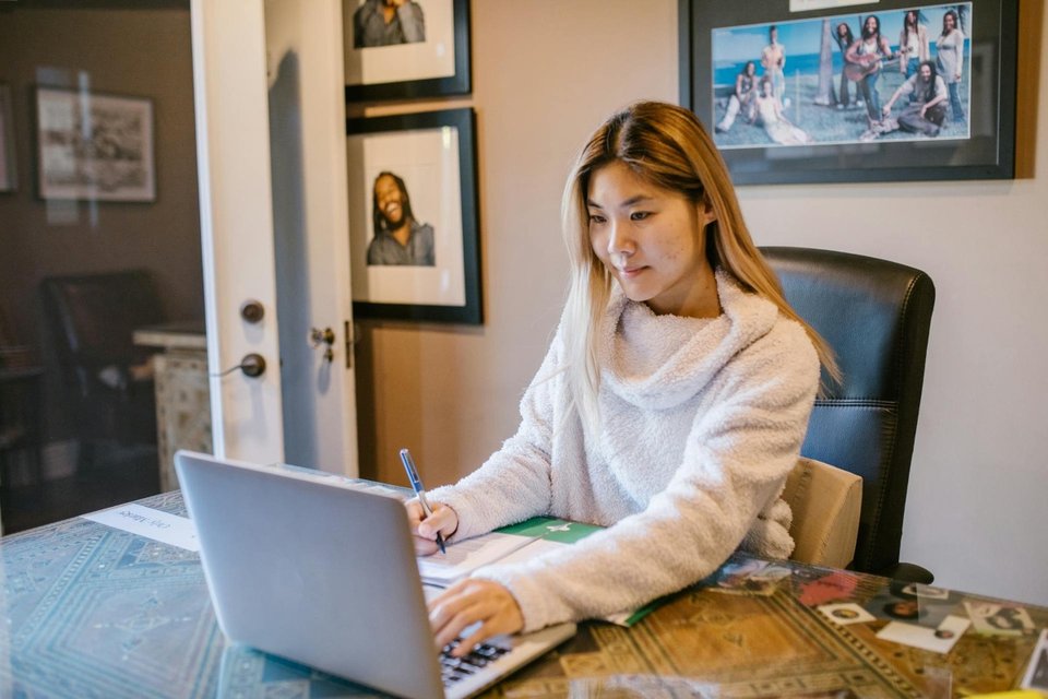 woman in white jumper using her laptop