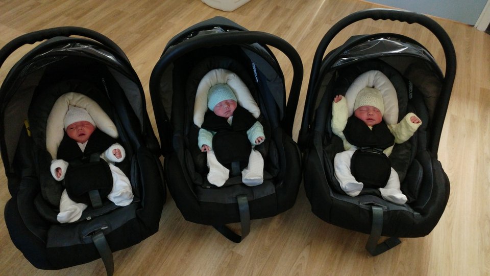 triplet babies each secured in a separate baby car seat