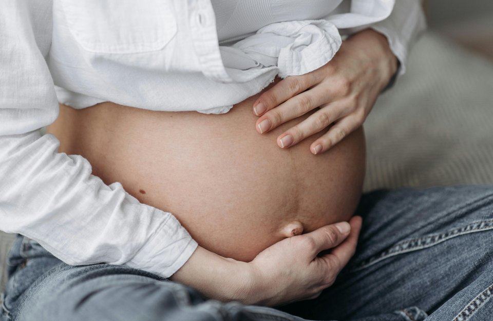 A close up image of a pregnant woman holding her belly
