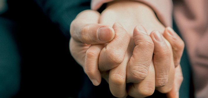 A close up of two people holding hands in a caring way
