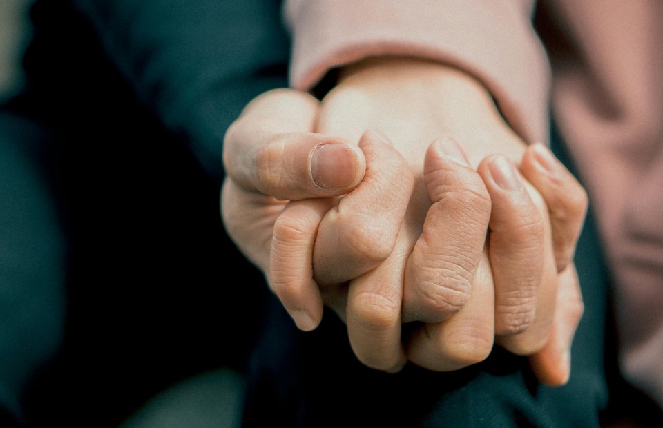 A close up of two people holding hands in a caring way