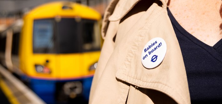 A close up of a label with a Babies on Board badge on it, with a London Overground train in the background