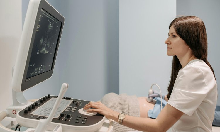 A side view of a sonographer sitting at an ultrasound machine
