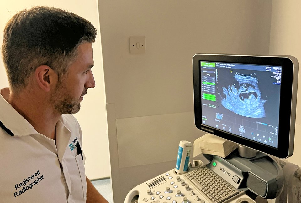 A sonographer looking at an ultrasound machine