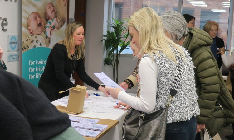 People stand around a table of resources with a woman looking at one she is holding