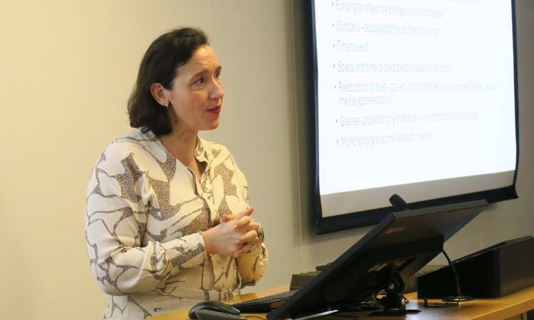 A woman stands at a lectern presenting