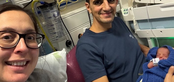 A man and woman sit together in hospital each holding a baby