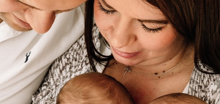 A close-up picture of a man and woman cuddling two babies