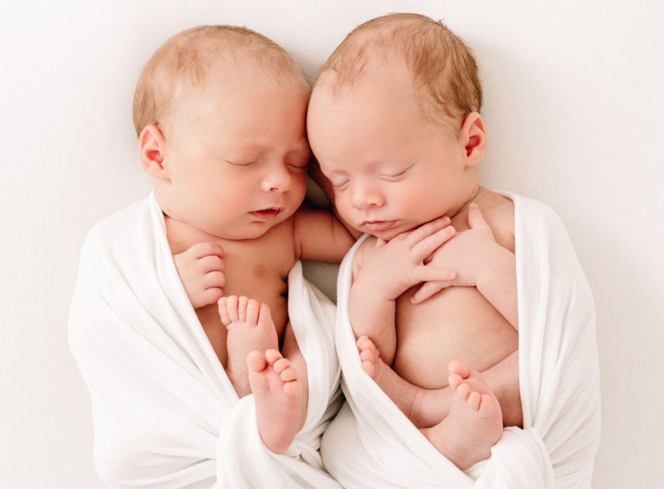 Two babies sleeping together wrapped in blankets
