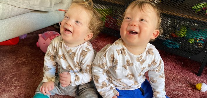 Twins sit on the floor laughing