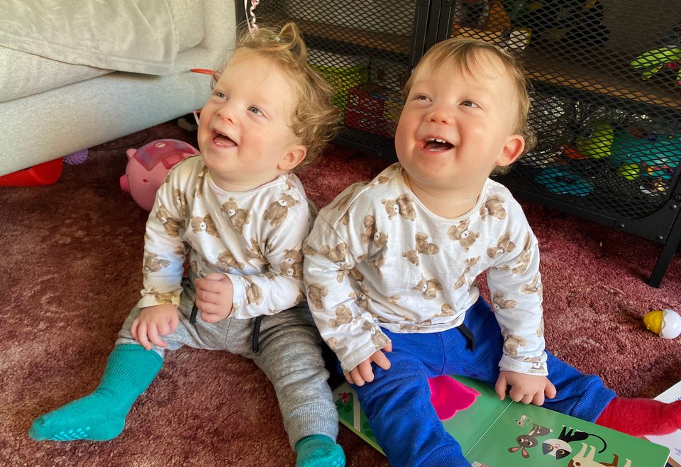 Twins sit on the floor laughing