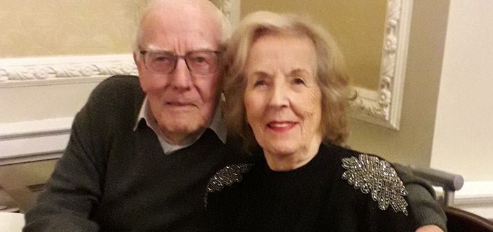 An elderly man and woman with their arms around each other