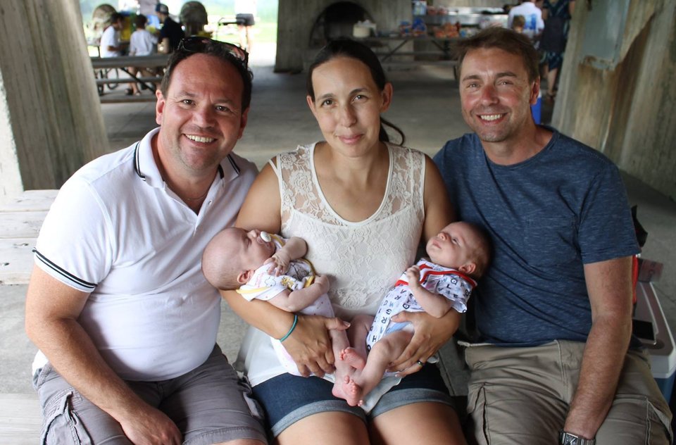 Two men sit either side of a woman who is holding twin babies