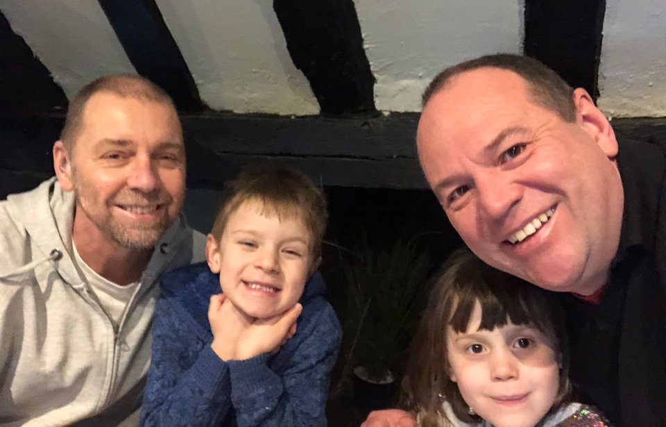 Two men sit either side of twin children