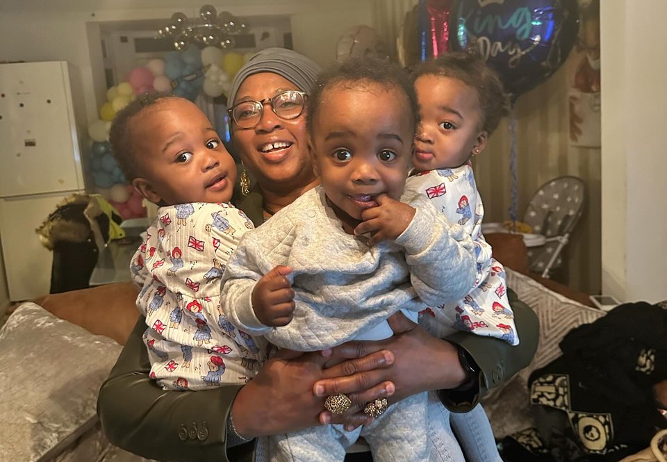 A woman with her arms around triplets