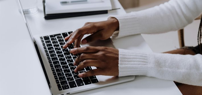 A side view of a pair of hands typing on a laptop