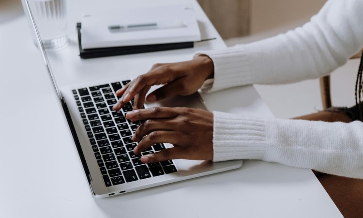 A side view of a pair of hands typing on a laptop
