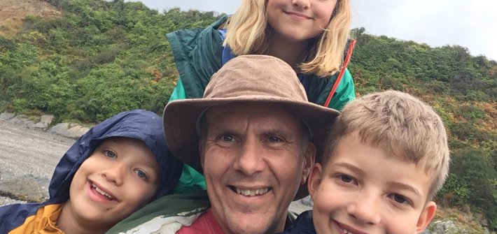 Selfie of a man surrounded by three children on a hike