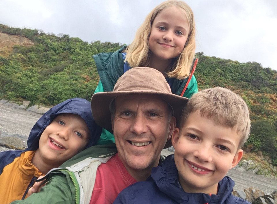 Selfie of a man surrounded by three children on a hike