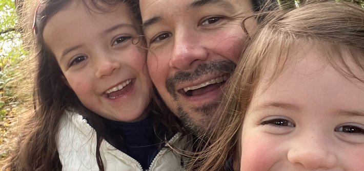 A man and twin girls take a selfie whilst walking in the woods