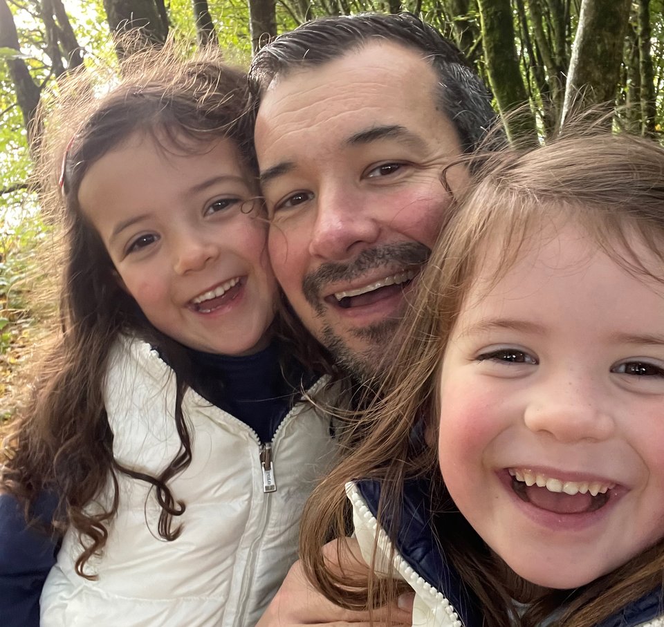 A man and twin girls take a selfie whilst walking in the woods