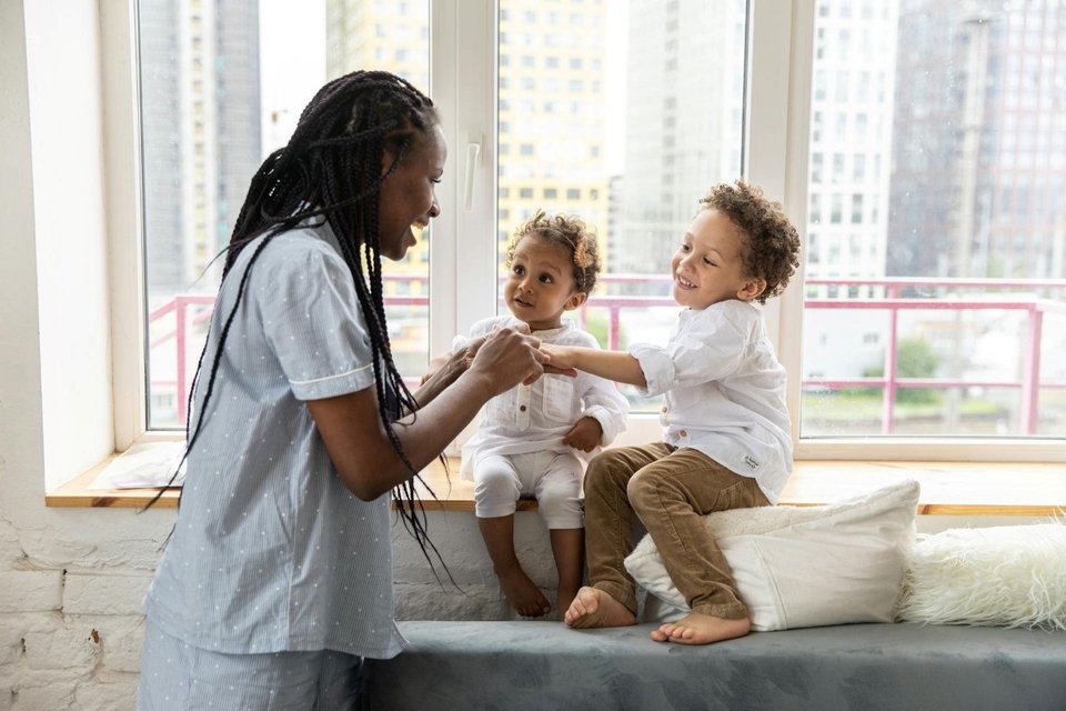 mother and smiling children on windowsill