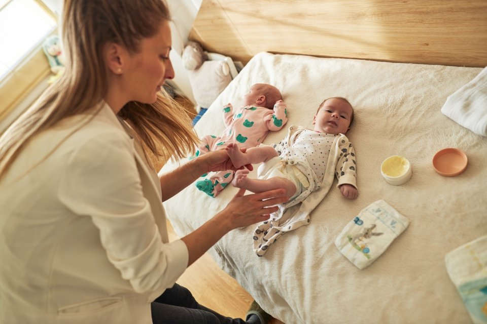 mother changing nappies for her newborn twins