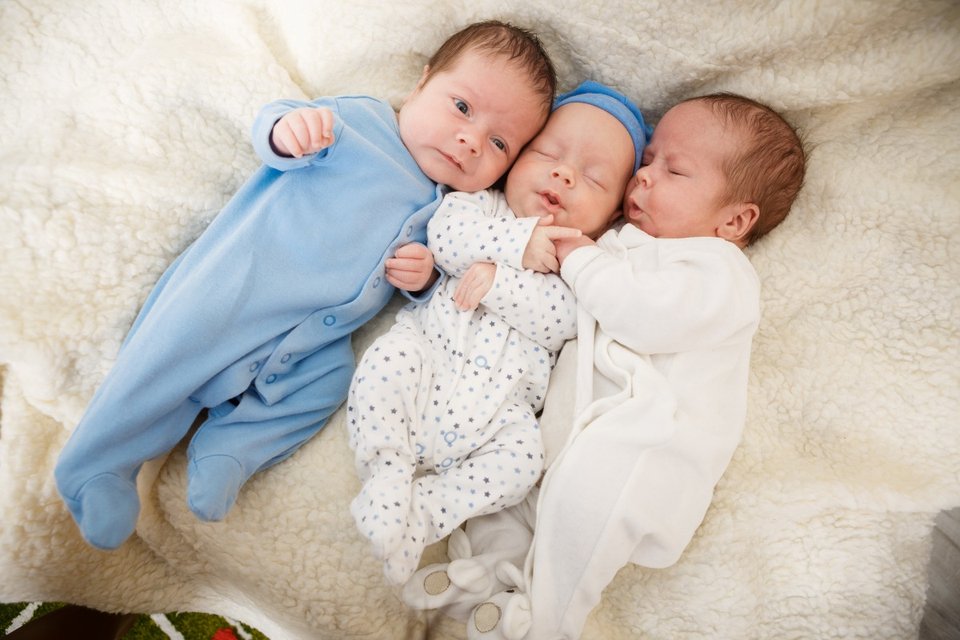 newborn triplets where two are asleep and one is awake