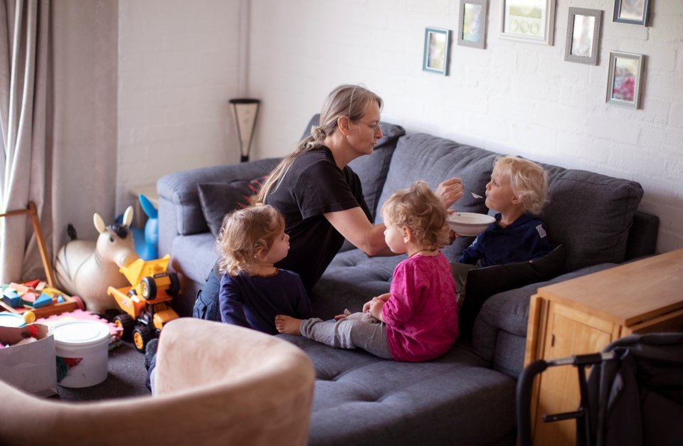 a grandmother looking after and feeding triplet children