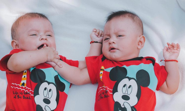 Twin babies lie next to each other