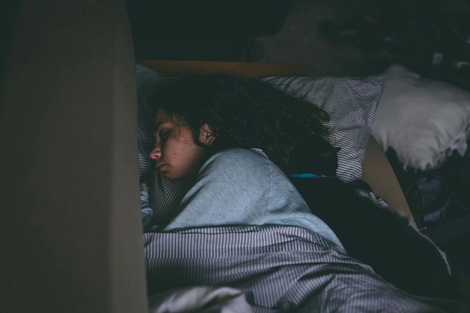 a woman sleeping on a bed in a dark bedroom