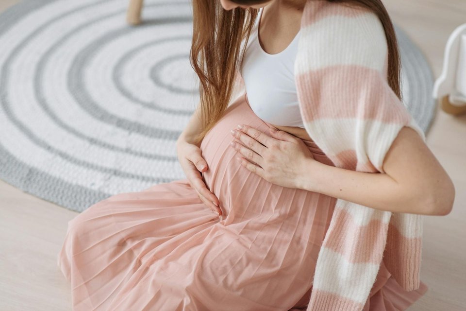 a pregnant woman slight hunched and holding her abdomen