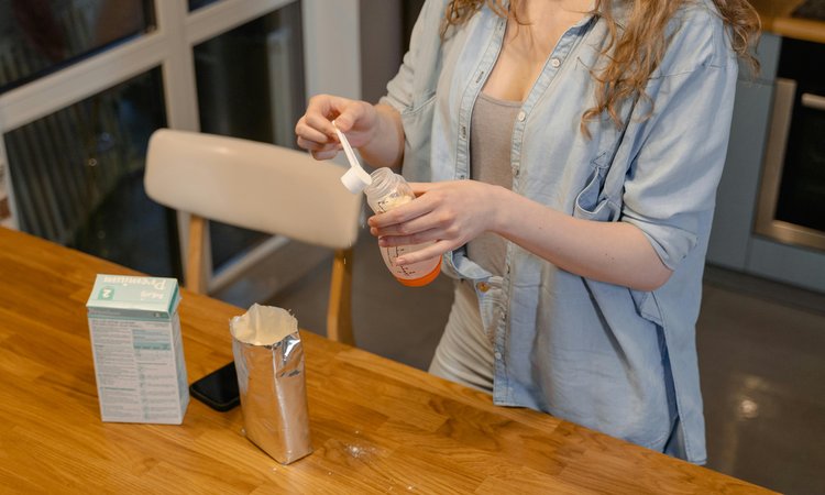A woman fills a baby bottle with formula