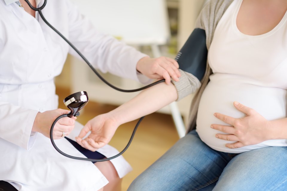 a pregnant woman having her blood pressure checked by a healthcare professional