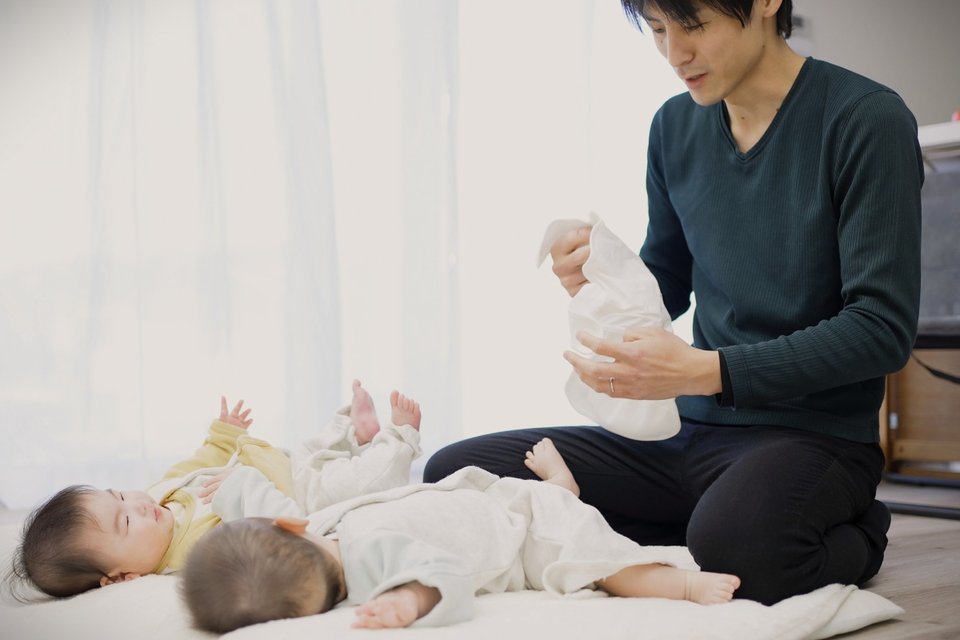 an Asian man changing twin babies' nappies