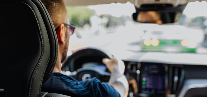 A picture taken over the shoulder of a man driving a car