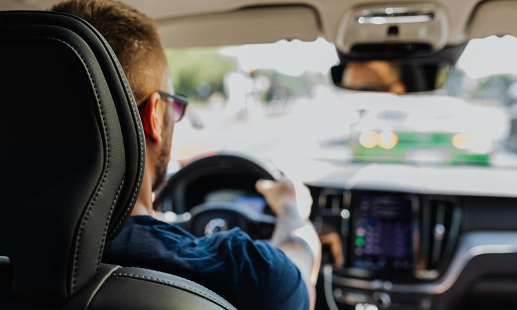 A picture taken over the shoulder of a man driving a car