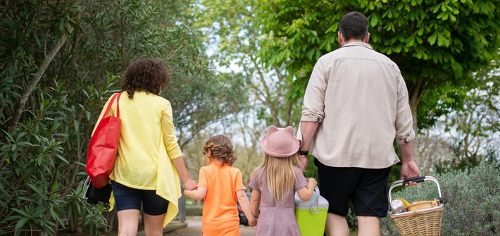A family of man, woman and two children seen walking along a path from behind