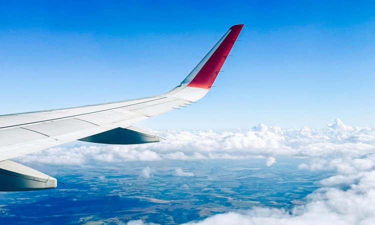 A plane wing flying high over land