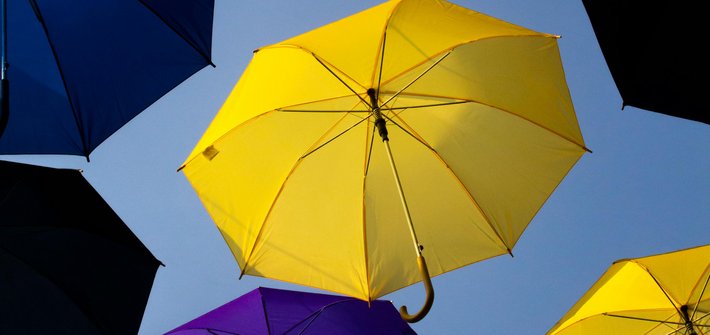 Yellow and purple umbrella hung open in the air seen from below